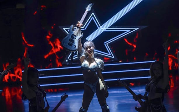 Performer holding guitar on stage at Calypso Cabaret, Bangkok.