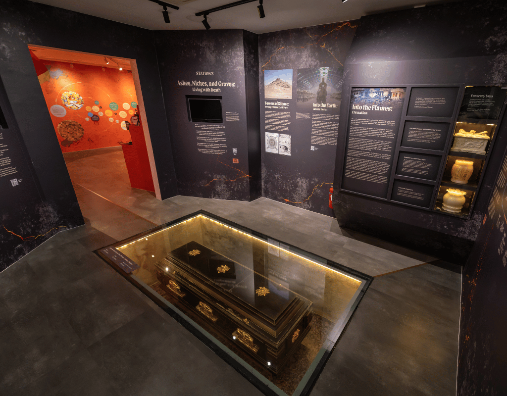 Exhibit at Hell's Museum showing a coffin beneath a glass floor, illustrating burial practices.