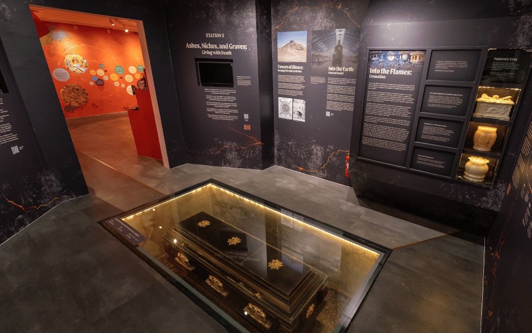 Exhibit at Hell's Museum showing a coffin beneath a glass floor, illustrating burial practices.
