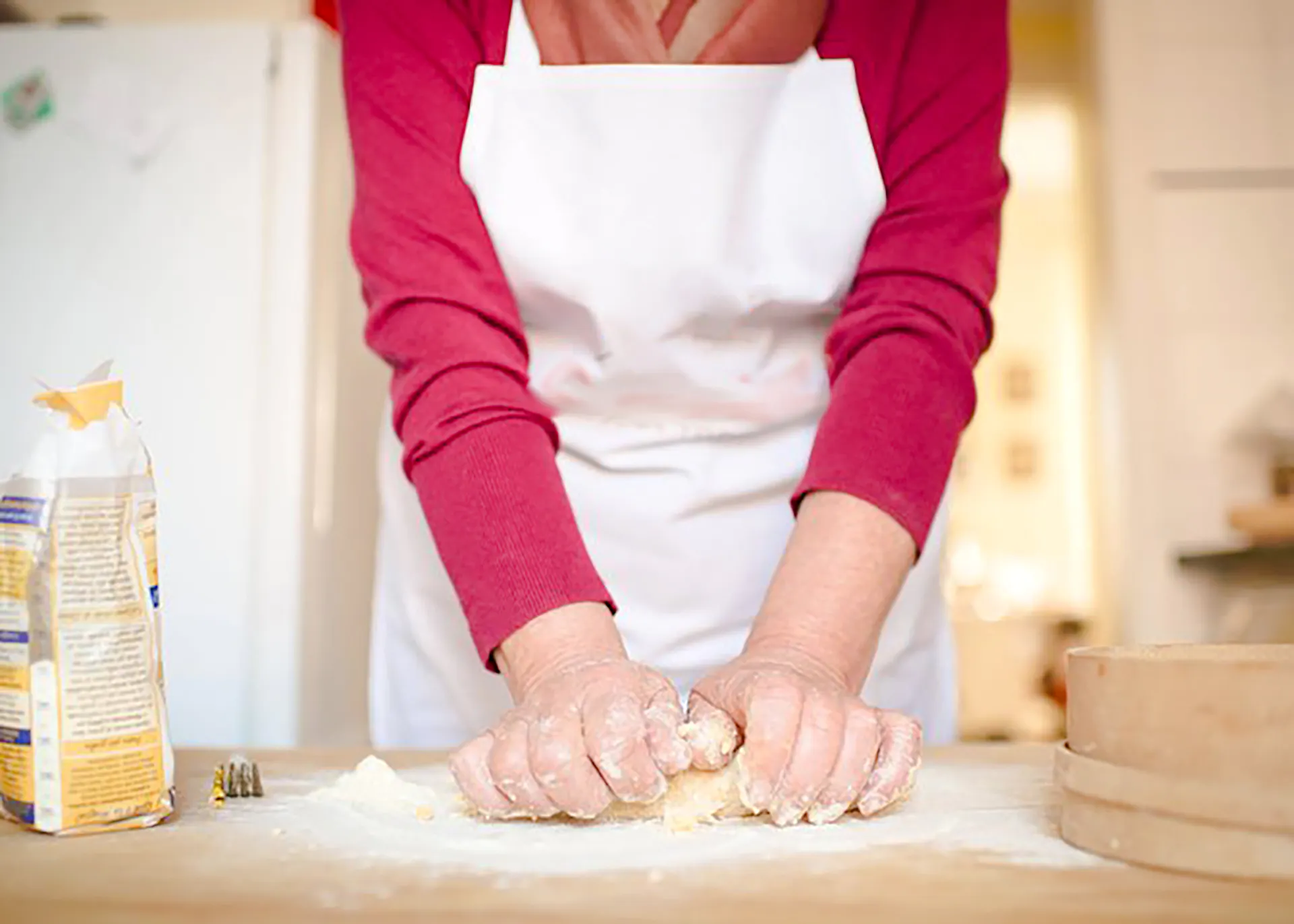 Hands kneading dough during a Genoese cooking lesson in Genoa.