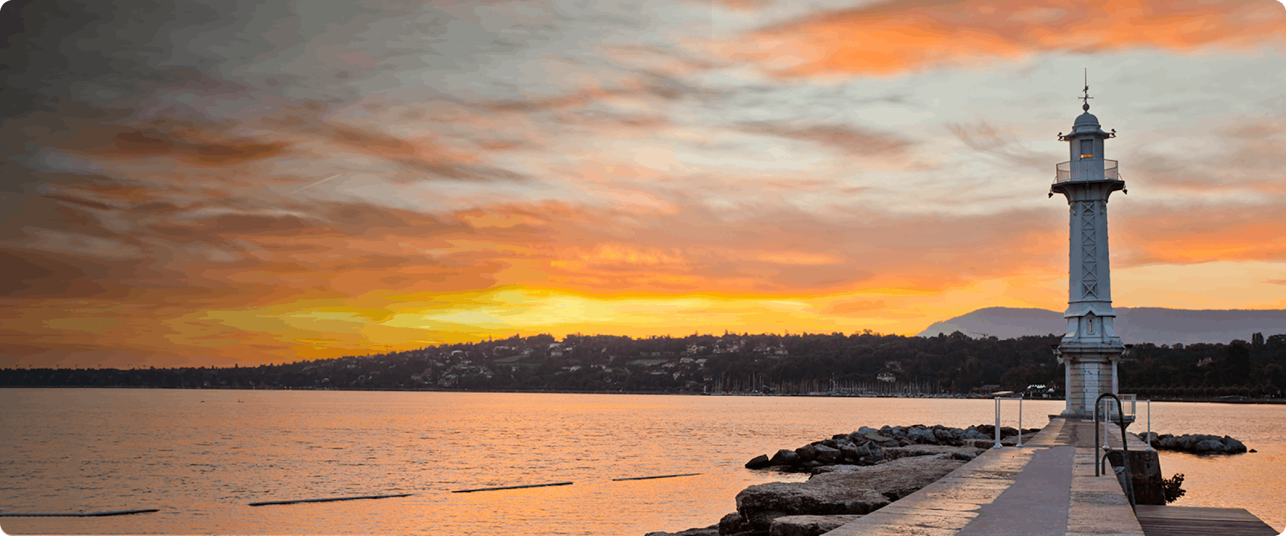 Lighthouse on Lake Geneva at sunset with distant hills.