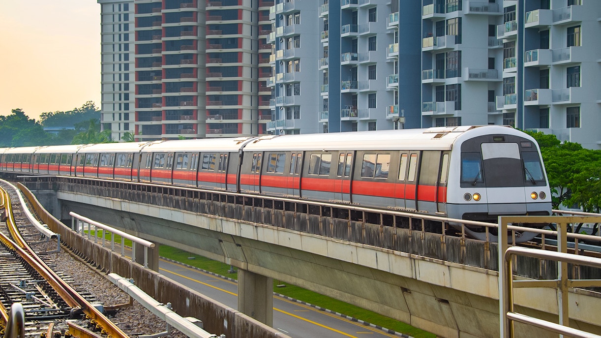 Metro train traveling through cityscape at dusk, Singapore