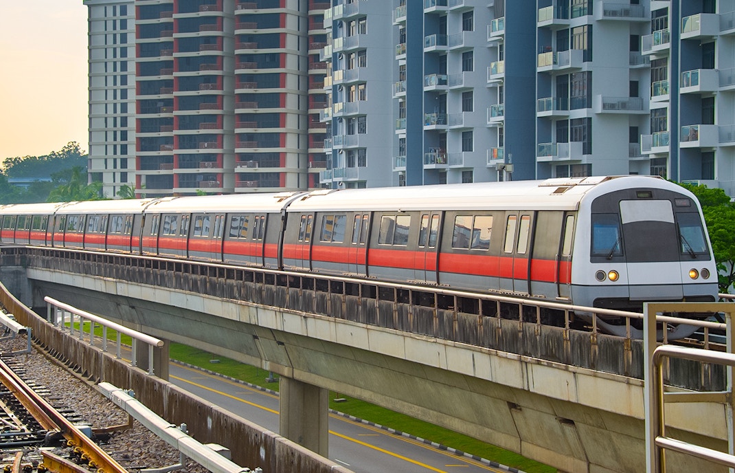 Metro train on elevated tracks during evening in Singapore.