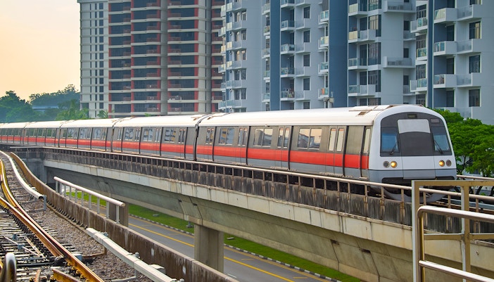 Metro train traveling through cityscape at dusk, Singapore