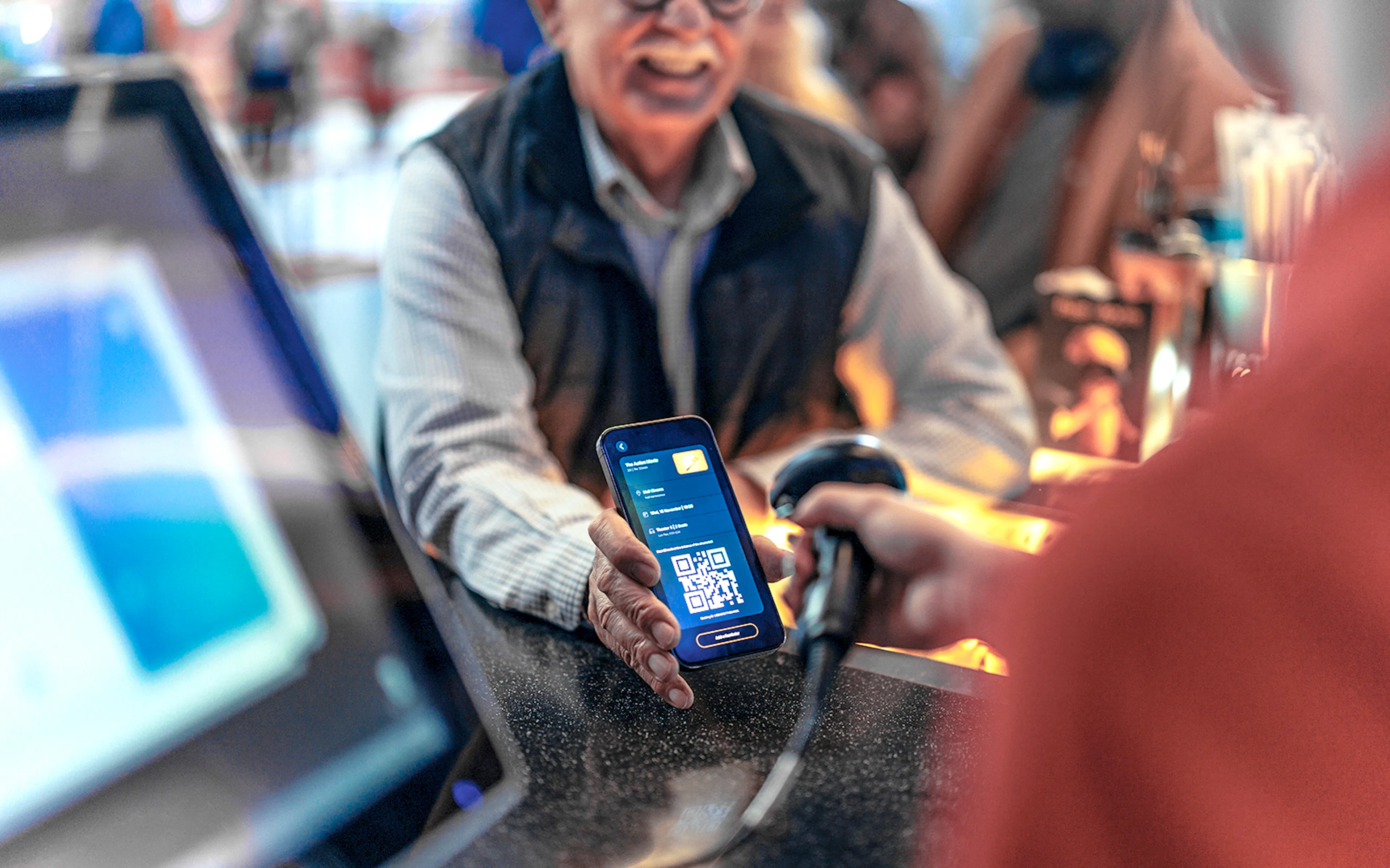 Scanning a digital voucher with a QR code at a ticket counter.