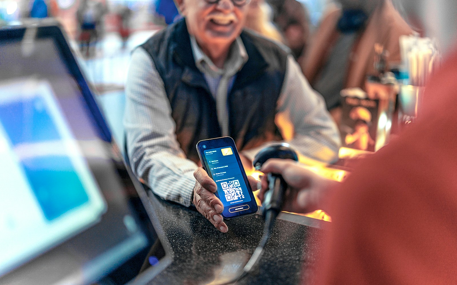 Scanning a digital voucher with a QR code at a ticket counter.