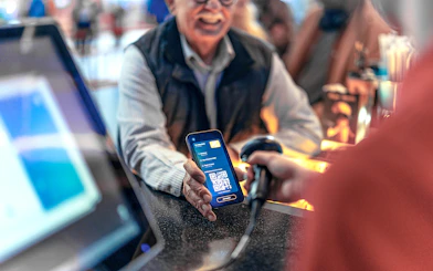 Scanning a digital voucher with a QR code at a ticket counter.