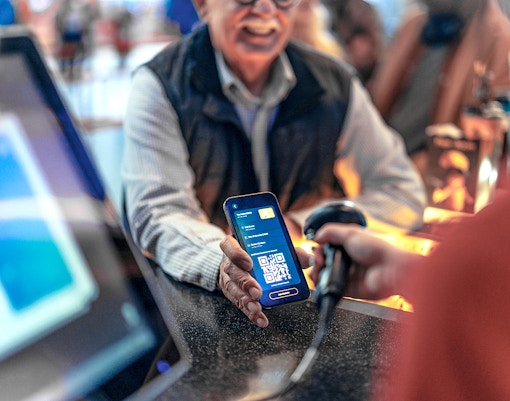 Scanning a digital voucher with a QR code at a ticket counter.