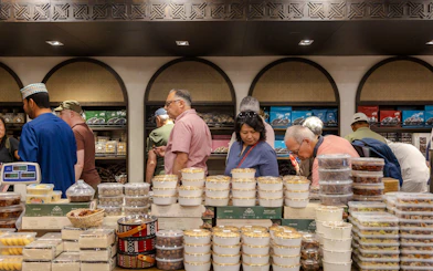 Tourists exploring a market with traditional Omani sweets during Nizwa and Oman Grand Canyon Tour.