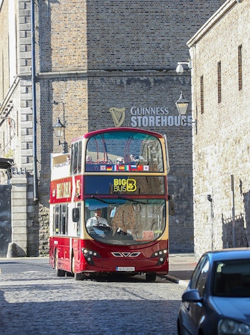 Big Bus Dublin tour passing by the Guinness Storehouse in Dublin, Ireland.
