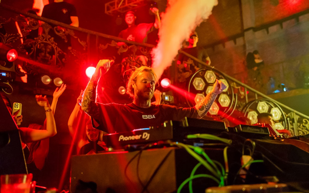 DJ performing at Atlas Super Night Club with vibrant lights and crowd.
