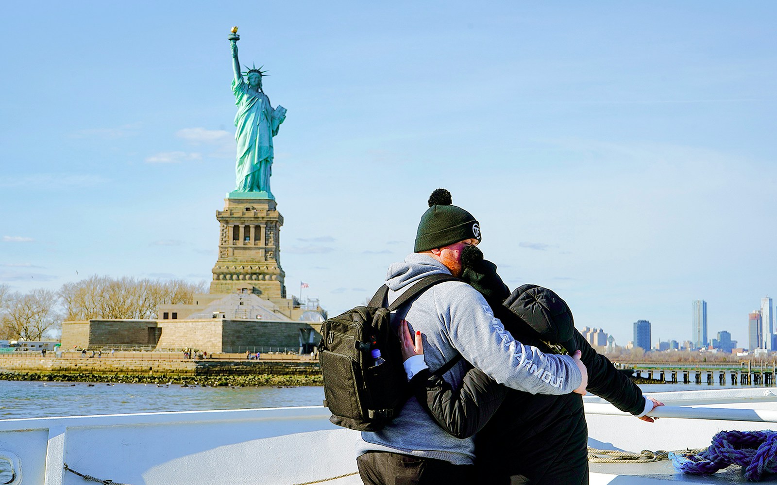 Couple embracing on a cruise with the Statue of Liberty in the background, New York City.