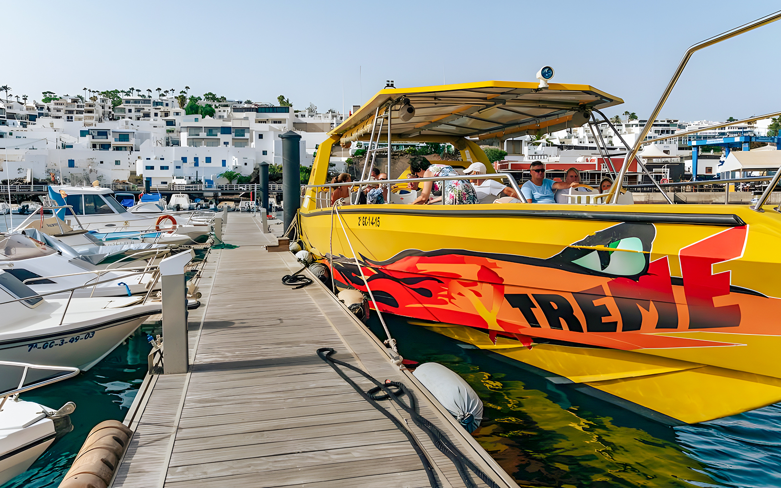 Yellow speedboat docked at marina, passengers boarding for Sunset Speedboat Dolphin Cruise.