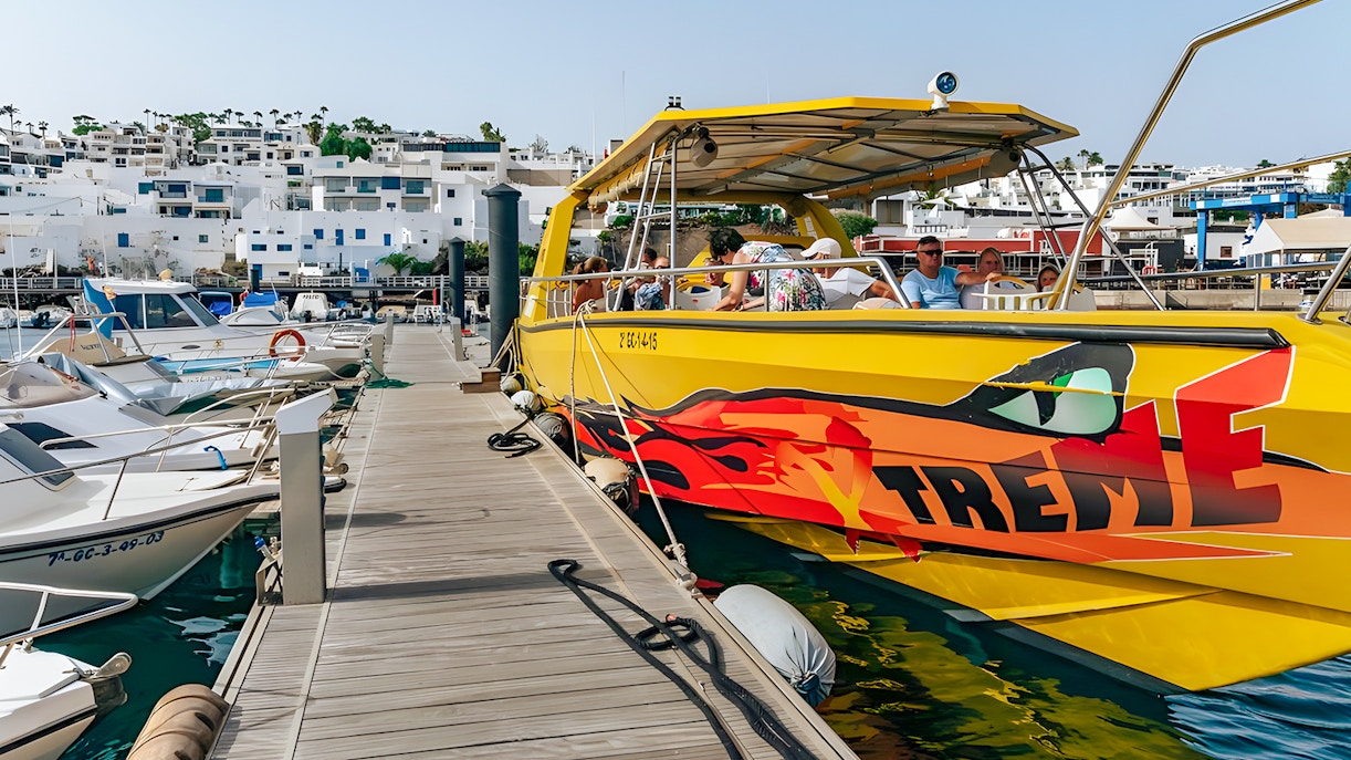 Yellow speedboat docked at marina, passengers boarding for Sunset Speedboat Dolphin Cruise.