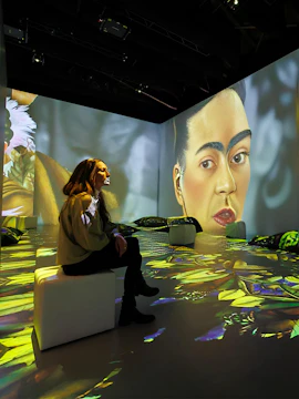 Visitor at Vienna Frida Kahlo immersive exhibition with large portrait projection.