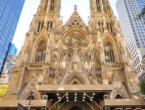 St. Patrick's Cathedral facade with visitors and a yellow taxi in New York City.