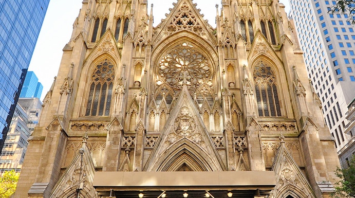 St. Patrick's Cathedral facade with visitors and a yellow taxi in New York City.
