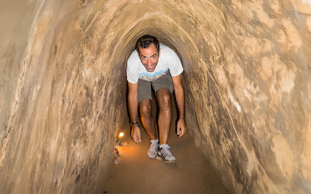 Person exploring narrow Cu Chi Tunnels on half-day tour in Vietnam.