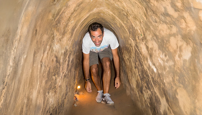 Person exploring narrow Cu Chi Tunnels on half-day tour in Vietnam.