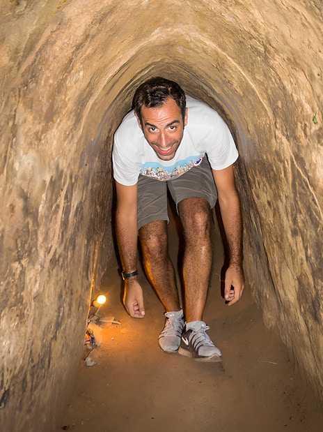 Person exploring narrow Cu Chi Tunnels on half-day tour in Vietnam.