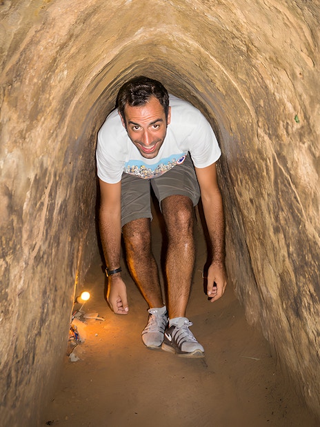 Person exploring narrow Cu Chi Tunnels on half-day tour in Vietnam.