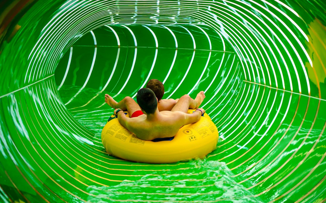 Two people on a yellow raft in the Andromeda slide, galaxy zone, Therme Bucharest.