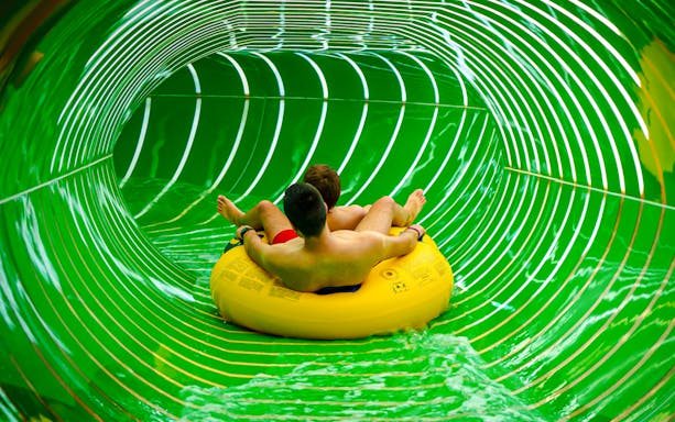Two people on a yellow raft in the Andromeda slide, galaxy zone, Therme Bucharest.