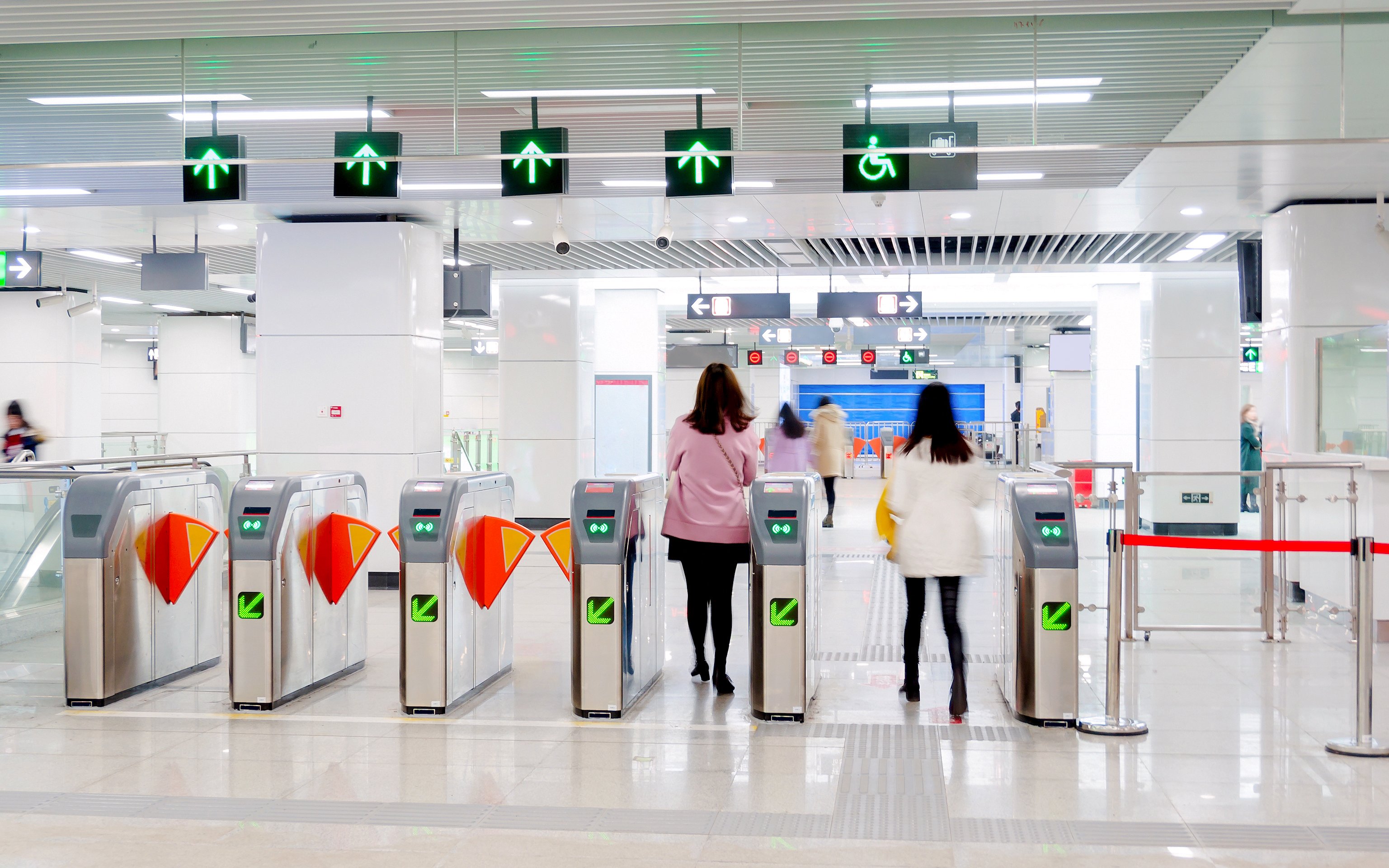 People passing through turnstiles at Beijing Metro station.