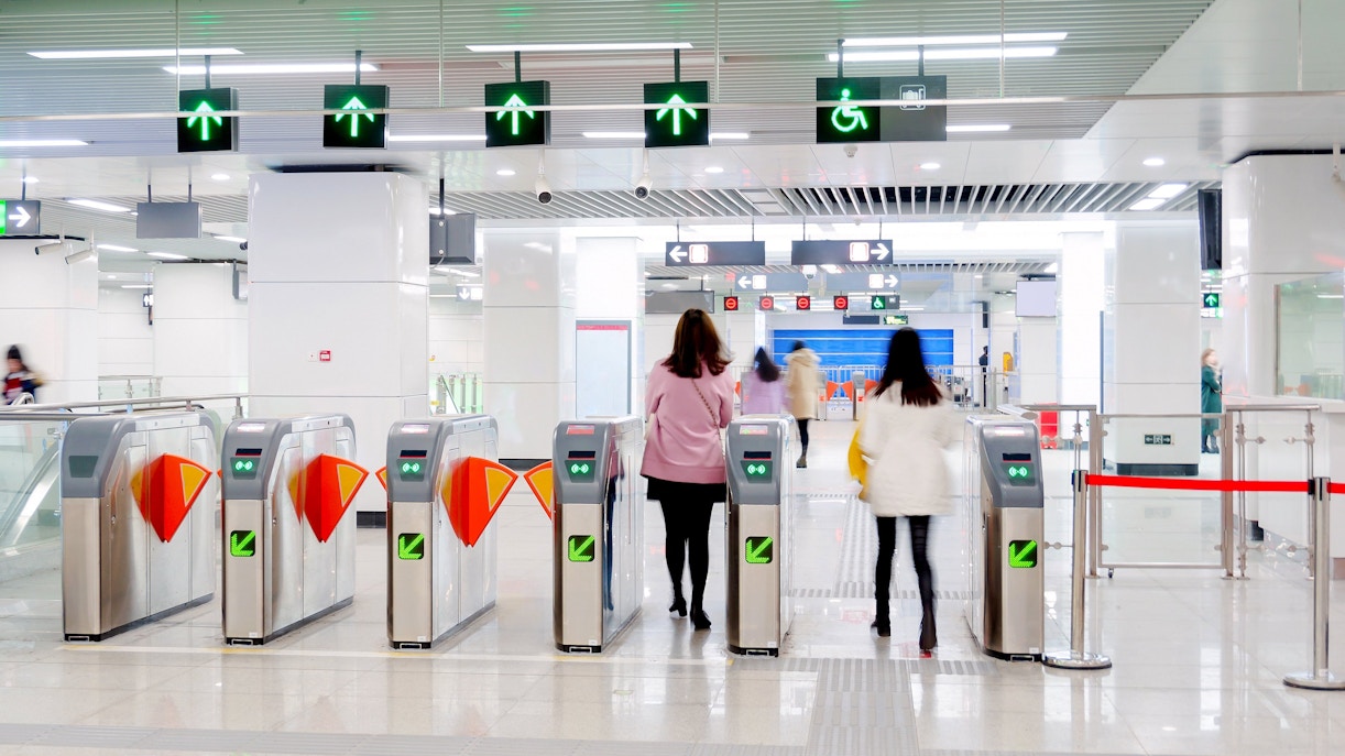 People passing through turnstiles at Beijing Metro station.