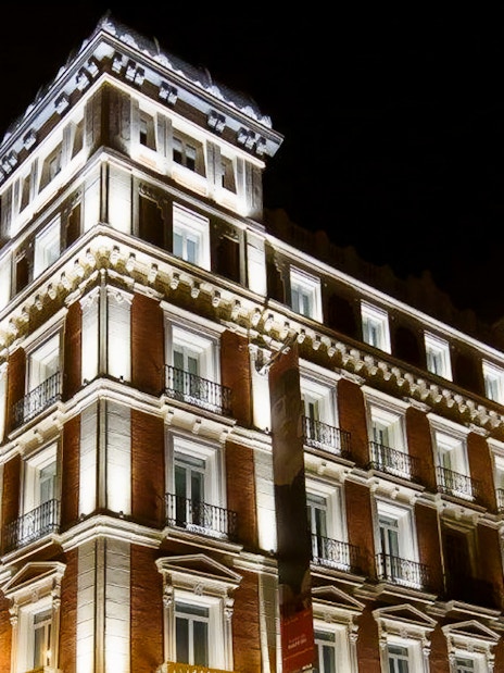 Illuminated facade of Fundación MAPFRE's Recoletos Room in Madrid at night.