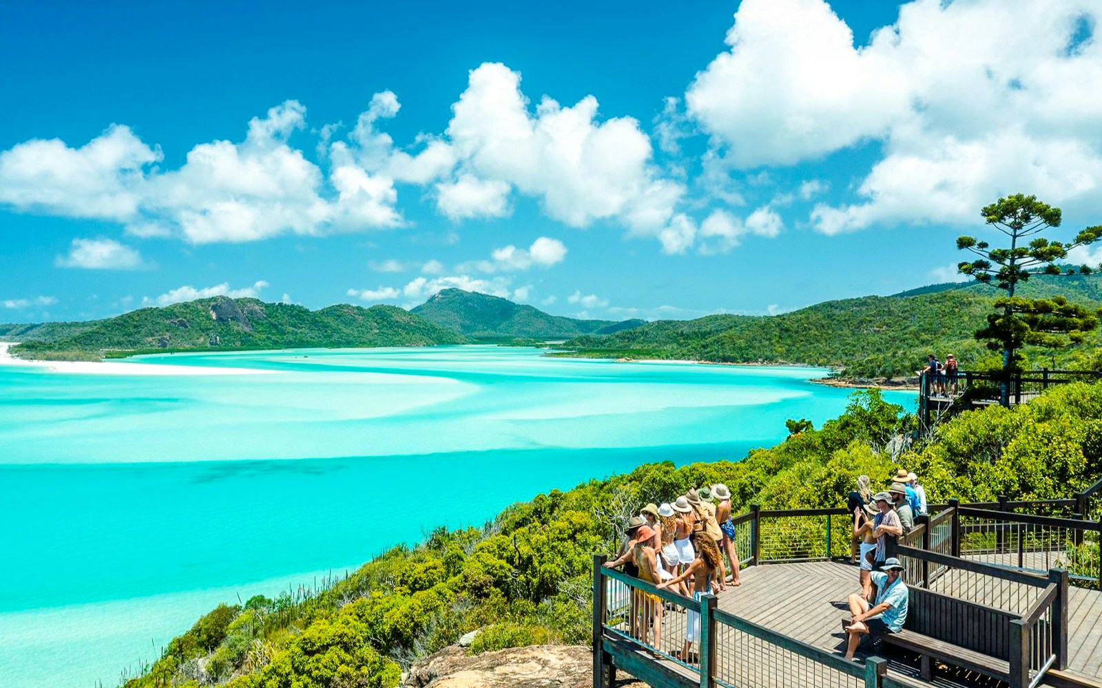 Visitors enjoying the view at Hill Inlet Lookout, Whitsundays, with turquoise waters and lush greenery.