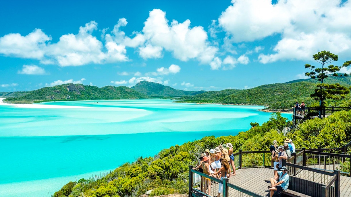 Visitors enjoying the view at Hill Inlet Lookout, Whitsundays, with turquoise waters and lush greenery.