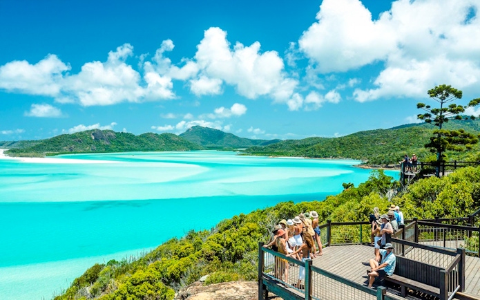 Visitors enjoying the view at Hill Inlet Lookout, Whitsundays, with turquoise waters and lush greenery.