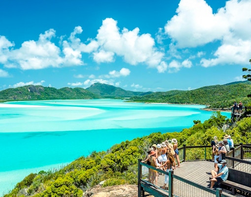 Visitors enjoying the view at Hill Inlet Lookout, Whitsundays, with turquoise waters and lush greenery.