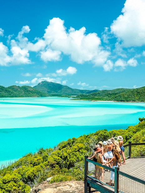 Visitors enjoying the view at Hill Inlet Lookout, Whitsundays, with turquoise waters and lush greenery.