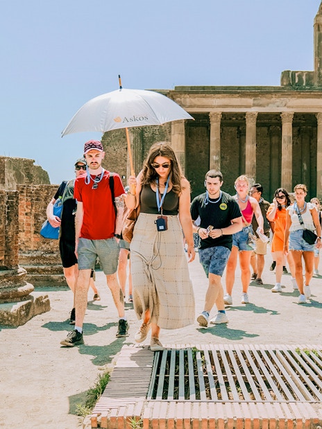 Tour group exploring ancient ruins at Pompeii with a guide.