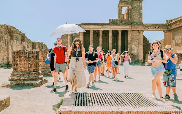 Tour group exploring ancient ruins at Pompeii with a guide.
