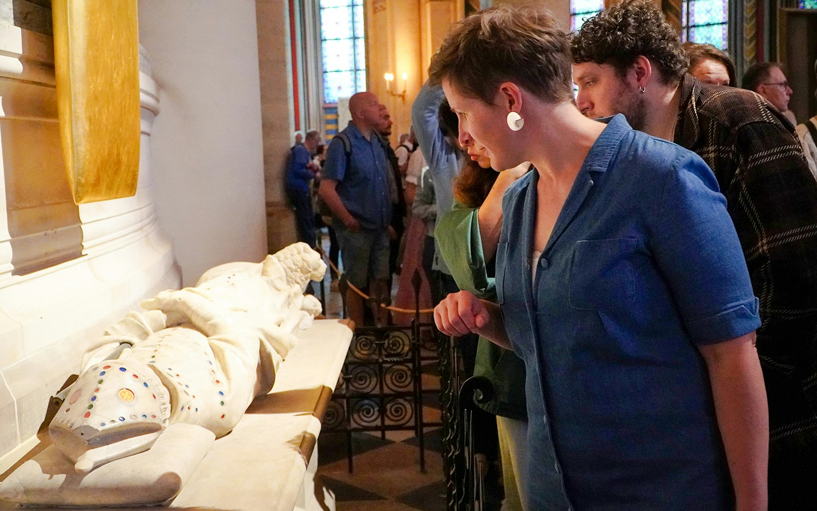 Guide examining a historical artifact inside Notre Dame Cathedral.
