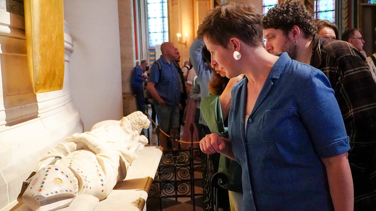 Guide examining a historical artifact inside Notre Dame Cathedral.