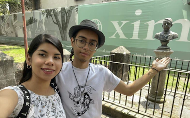 Couple exploring a historic site in Mexico City with a statue in the background.