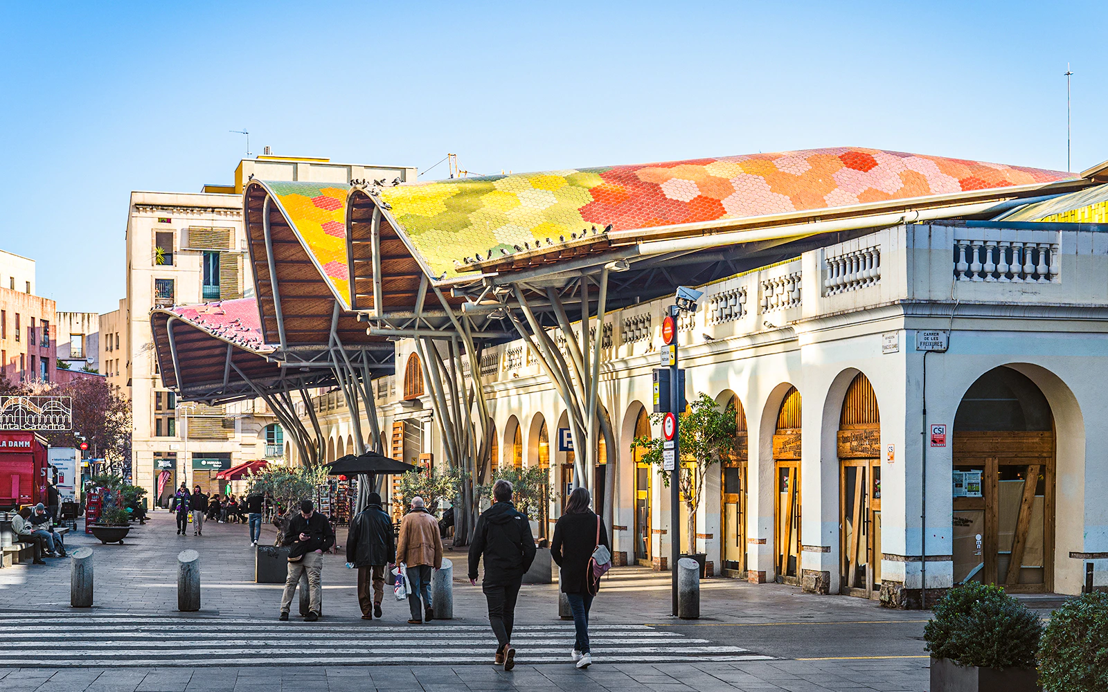 Santa Caterina Market in Barcelona with colorful mosaic roof and people walking nearby.