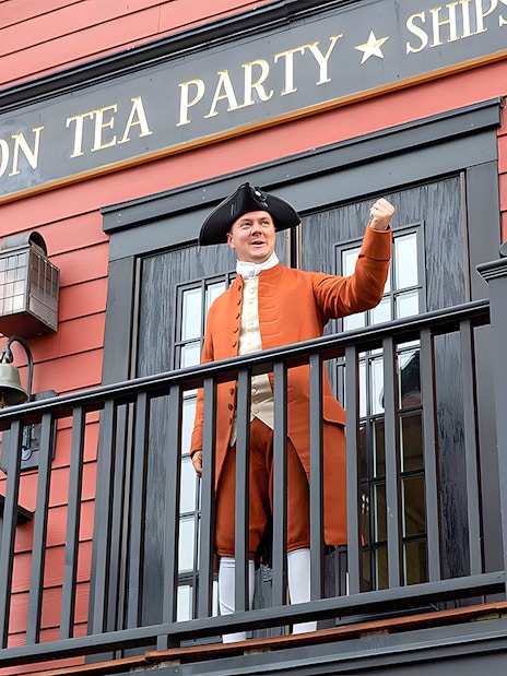 Boston Tea Party Ship and Museum exterior with historical reenactor on balcony.