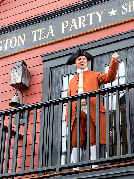 Boston Tea Party Ship and Museum exterior with historical reenactor on balcony.