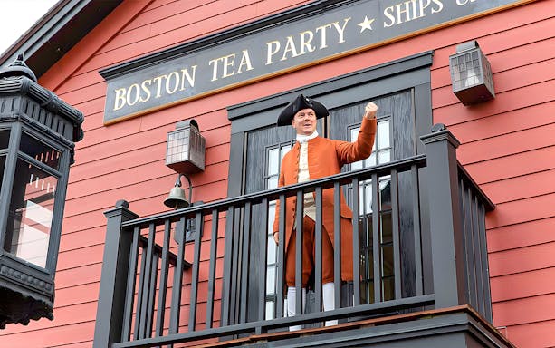 Boston Tea Party Ship and Museum exterior with historical reenactor on balcony.