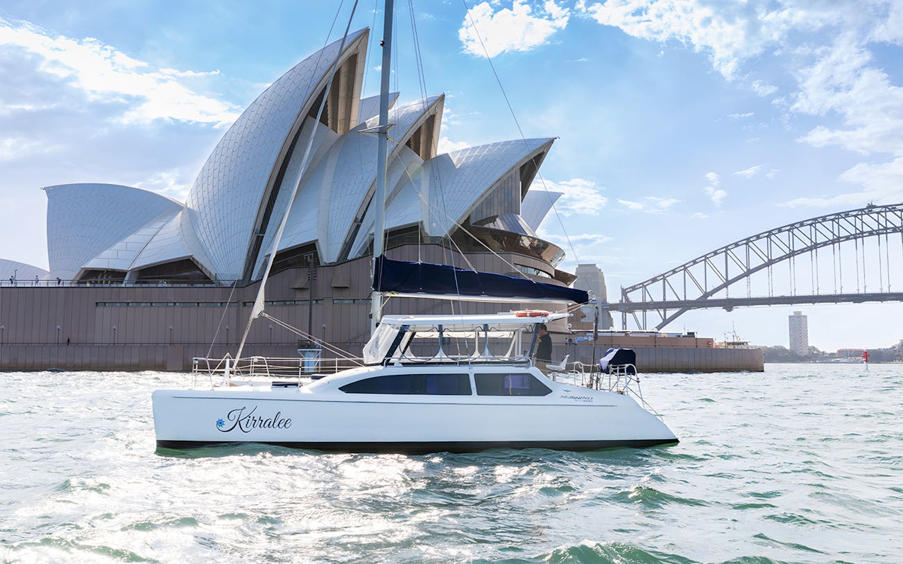 Catamaran Kirralee cruising near Sydney Opera House and Harbour Bridge during Vivid Sydney.