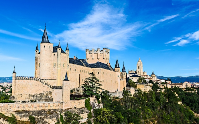 Alcazar of Segovia castle with turrets and surrounding landscape.