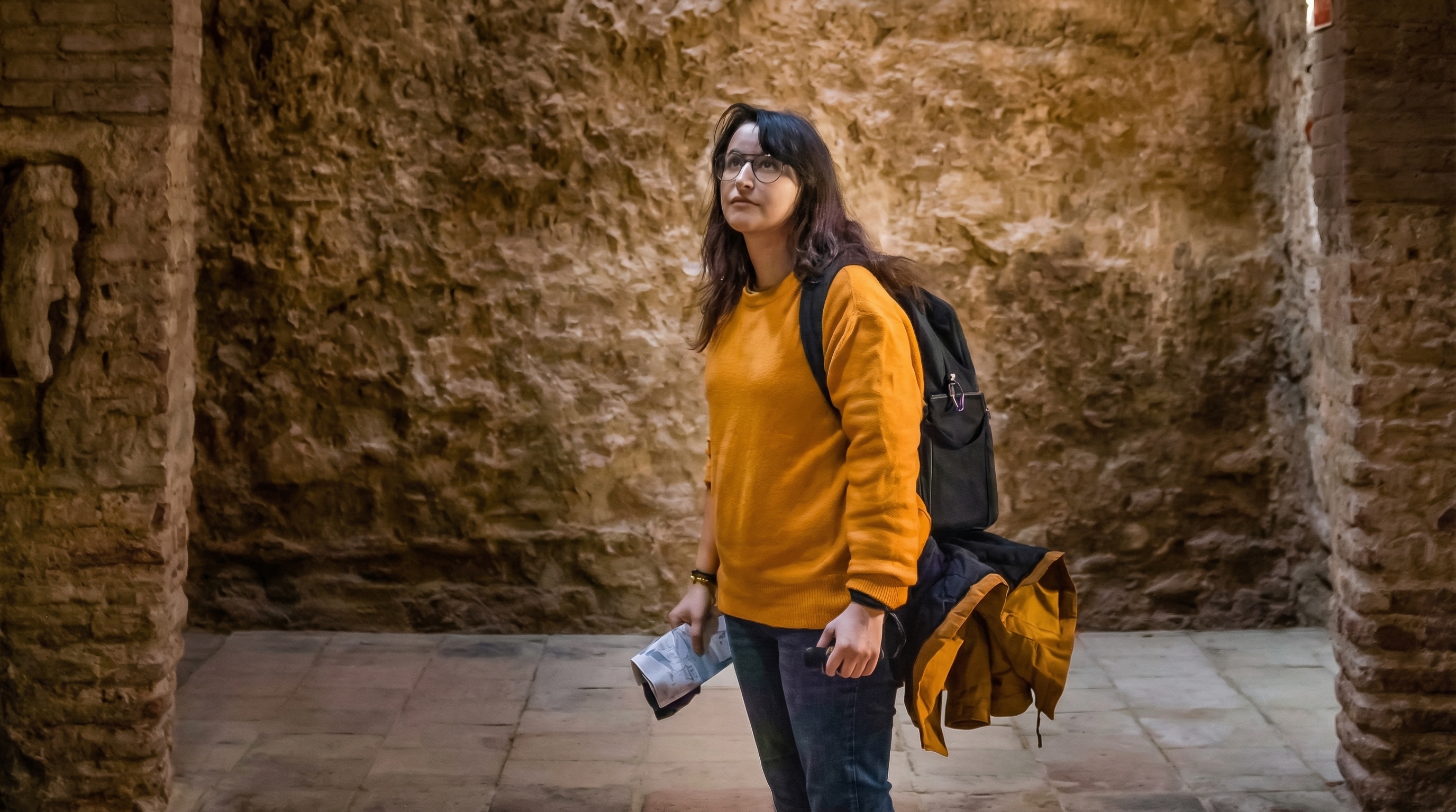 Tourist exploring historic stone vault interior.