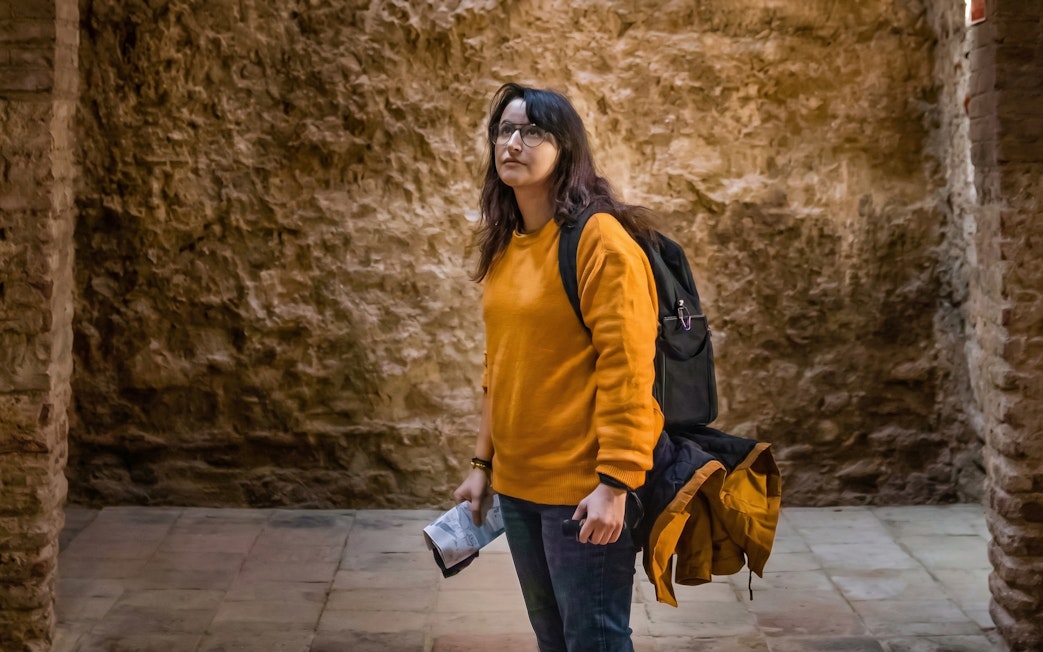 Tourist exploring historic stone vault interior.