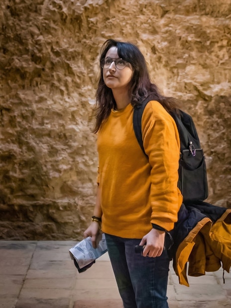 Tourist exploring historic stone vault interior.