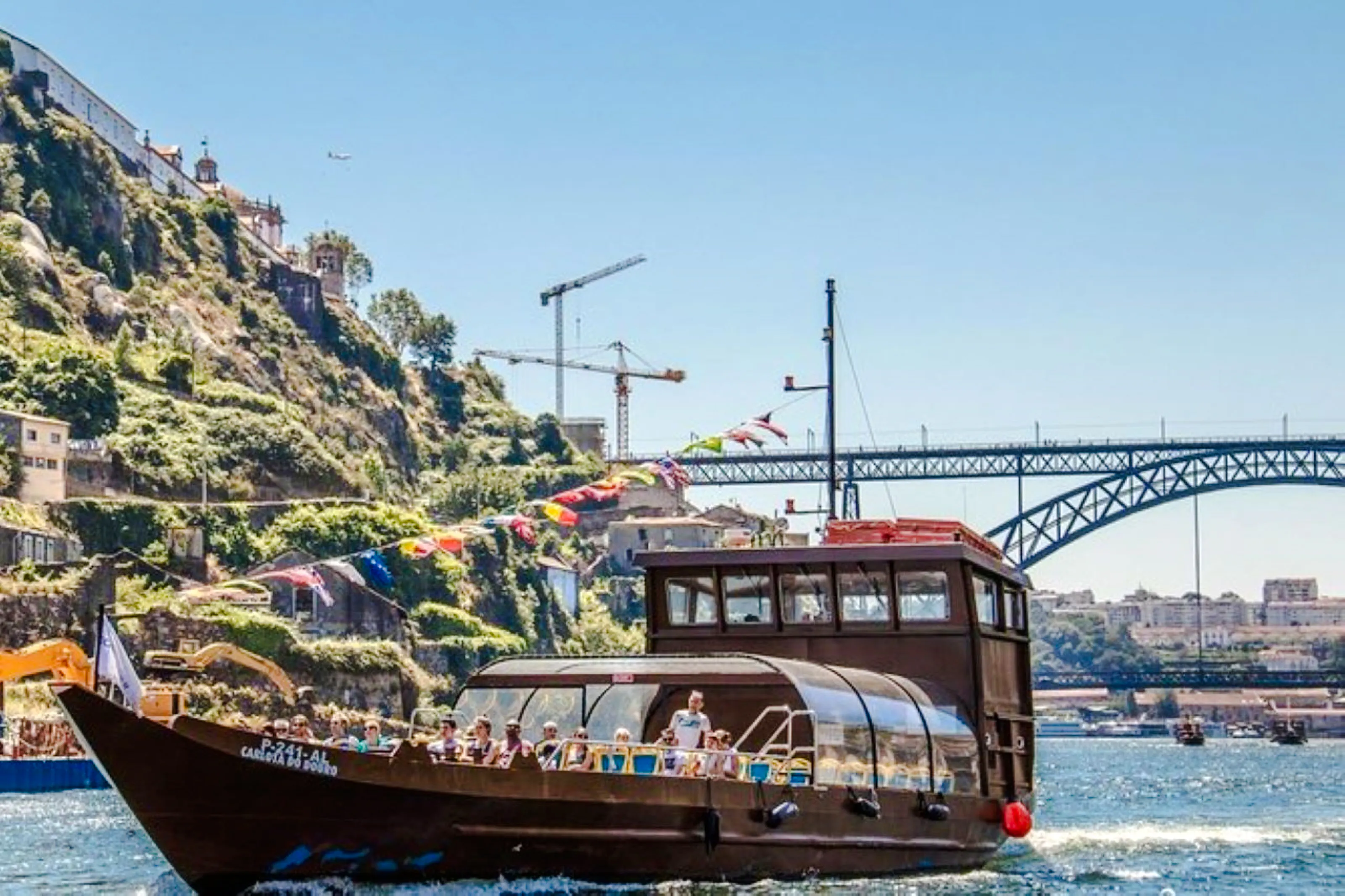 Boat cruising on the Douro River with Porto's Dom Luís I Bridge in the background.